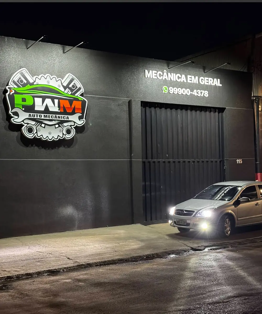Fachada da PWM Auto Mecânica à noite, com a logo iluminada e o letreiro Mecânica em Geral, no número 115